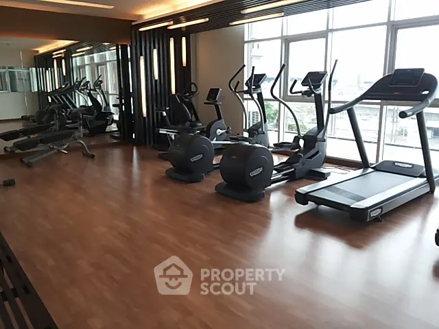 Modern gym with state-of-the-art equipment and large windows offering a bright and airy workout space.
