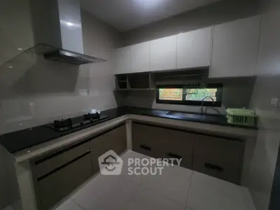 Modern kitchen with sleek cabinetry and gas stove, featuring a minimalist design and ample natural light.