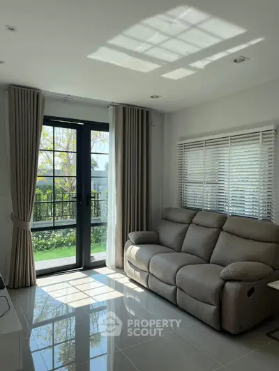 Bright living room with modern sofa and large window overlooking garden