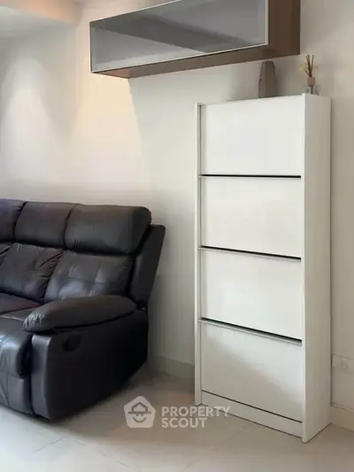 Modern living room with sleek white storage and leather sofa, perfect for stylish urban living.