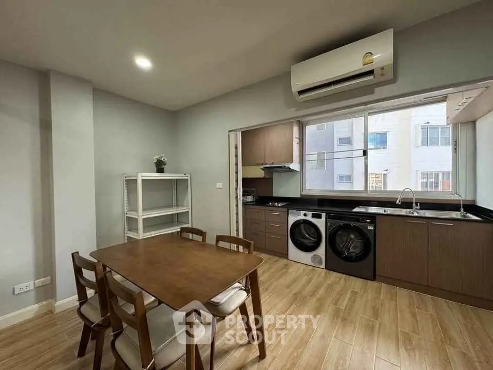 Modern kitchen with dining area, featuring wooden flooring and built-in appliances.