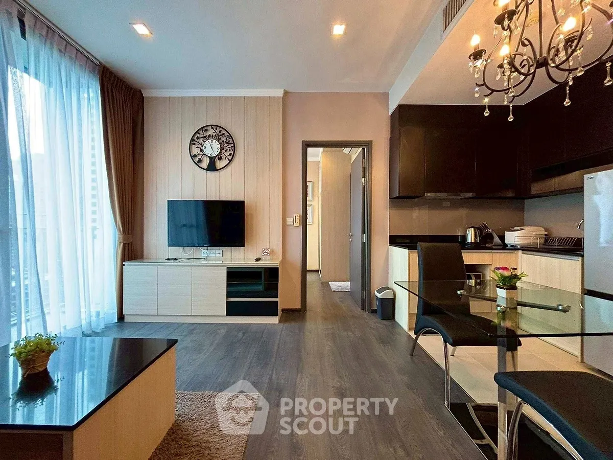 Modern living room with open kitchen, elegant decor, and natural light.