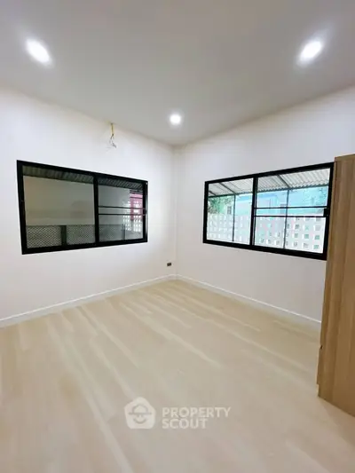 Spacious empty room with large windows and wooden flooring, perfect for customization.