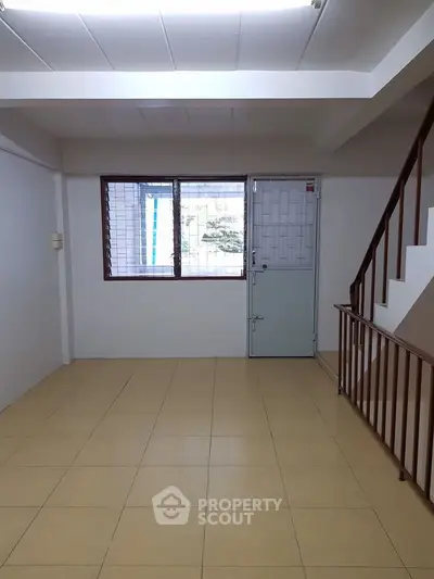 Spacious interior with tiled flooring and staircase, ideal for versatile use.