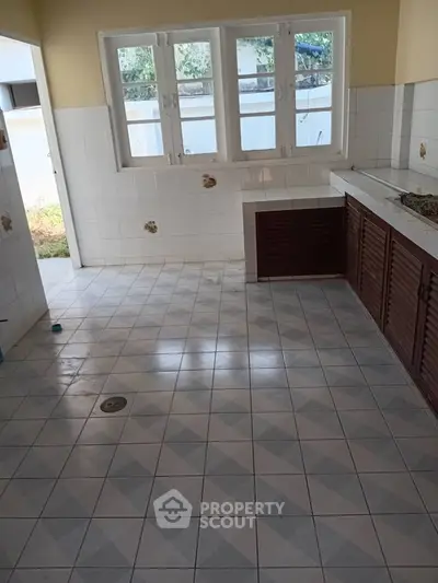 Spacious kitchen with tiled floor and ample natural light from large windows.