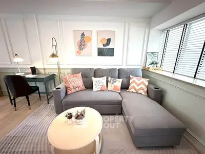 Stylish living room with modern gray sofa, chic decor, and natural light from large windows.