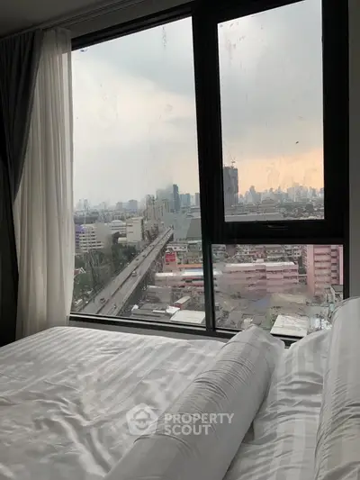 Spacious bedroom with stunning city view through large windows, perfect for urban living.