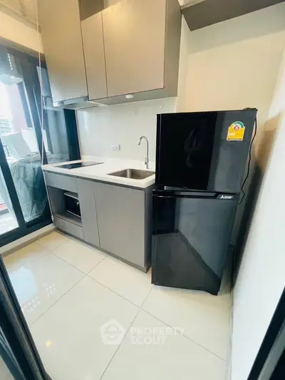Modern kitchen with sleek cabinetry and black refrigerator in a stylish apartment.