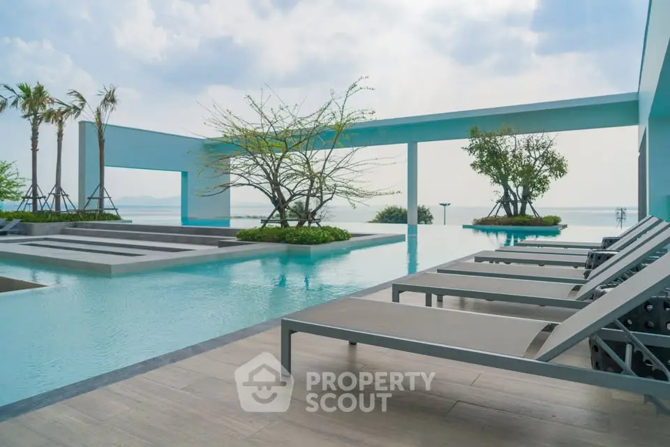Luxurious poolside area with stunning ocean view and modern lounge chairs, perfect for relaxation and leisure.