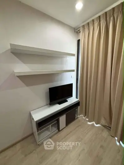 Modern living room with sleek TV stand and floating shelves, featuring elegant curtains and wooden flooring.