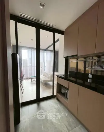Modern kitchen with sleek cabinetry and open layout leading to a stylish living area.