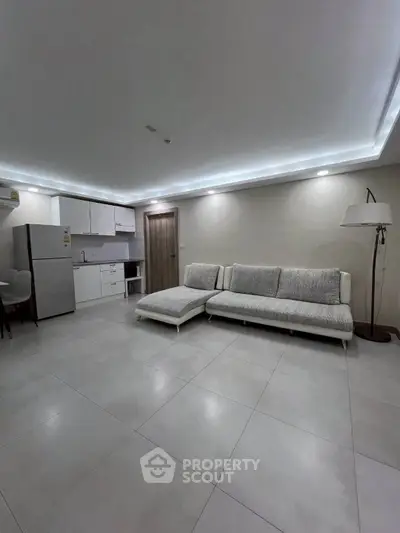 Modern living room with sleek kitchen and stylish furniture in open layout.