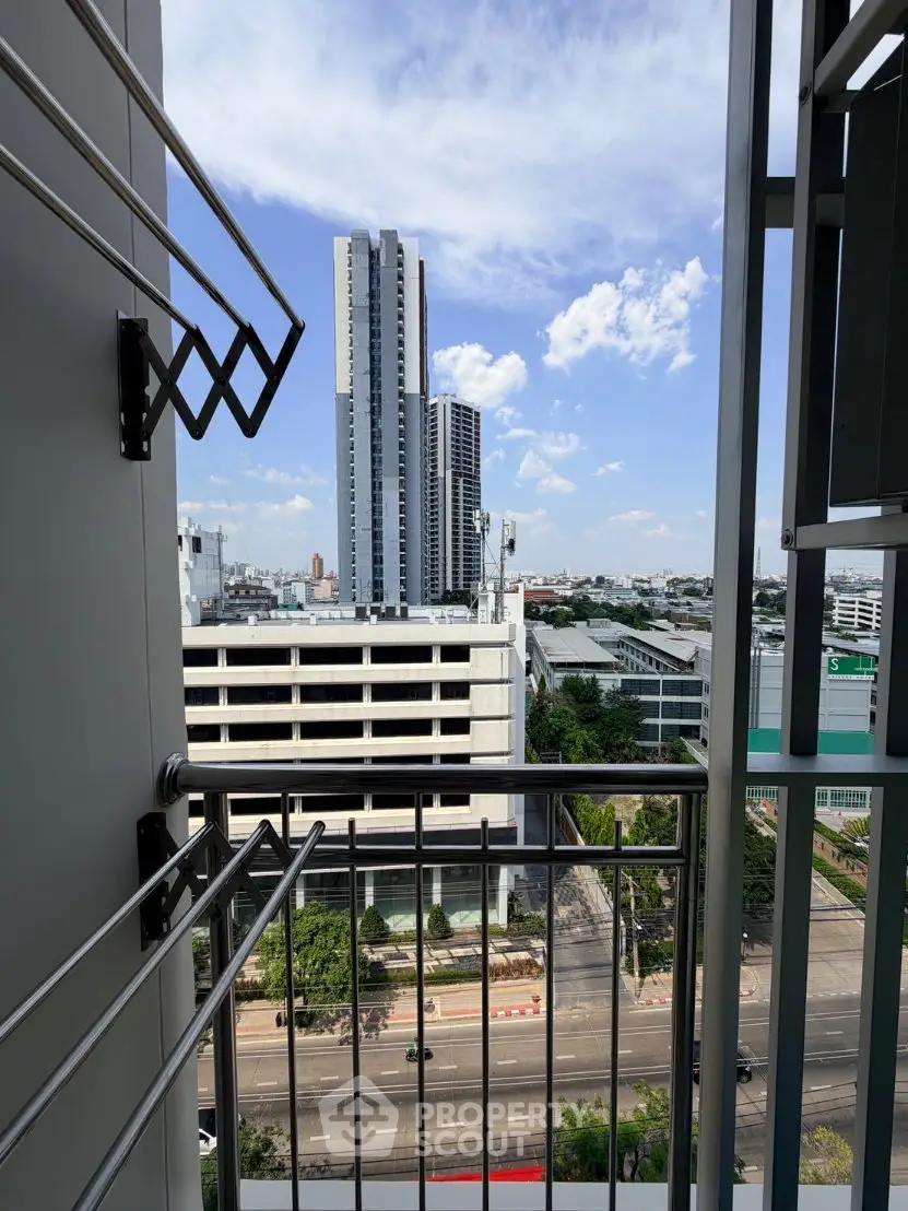 Stunning city view from a high-rise balcony with modern railing and clear blue sky.
