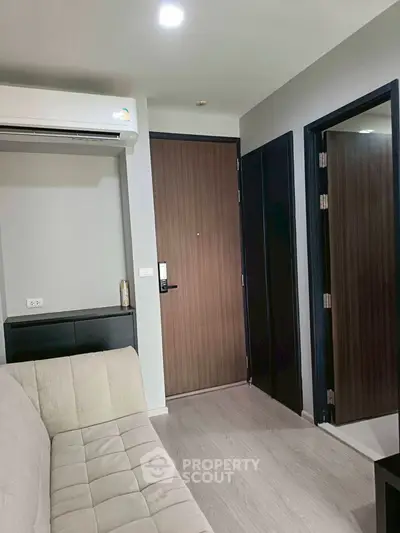 Modern apartment interior with sleek design and neutral tones, featuring a comfortable sofa and stylish wooden door.