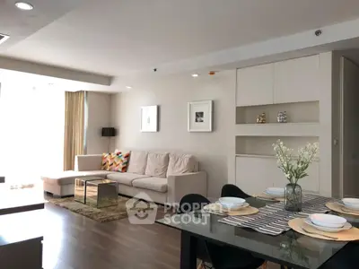 Modern living room with stylish decor and dining area, featuring a cozy sofa and elegant table setting.