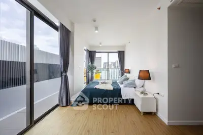 Modern bedroom with large windows and city view, featuring stylish decor and natural light.