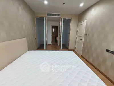 Spacious bedroom with modern design and ample natural light, featuring a comfortable bed and stylish decor.