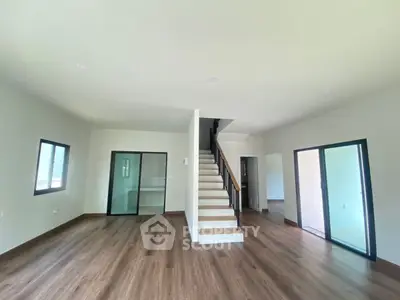 Spacious modern living room with wooden flooring and staircase, perfect for family gatherings.