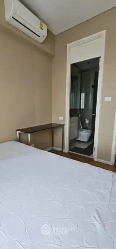 Cozy bedroom with ensuite bathroom and air conditioning in modern apartment.