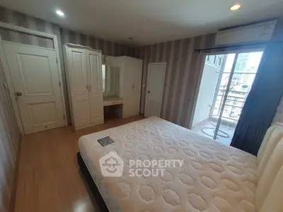 Spacious bedroom with balcony access and city view, featuring elegant wardrobe and vanity set.