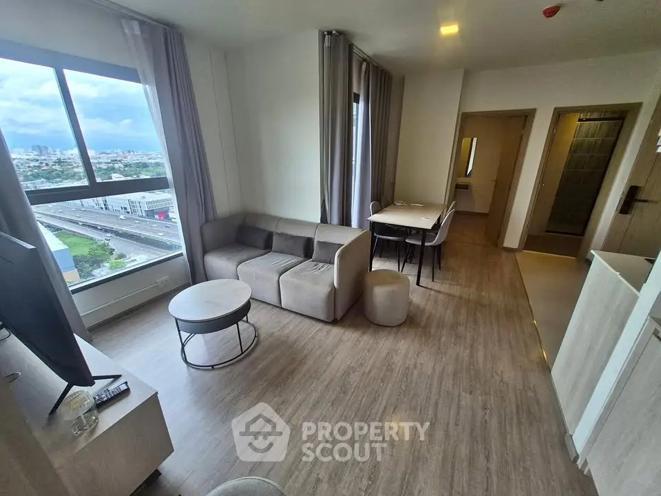 Modern living room with large window and stylish furniture in a high-rise apartment.