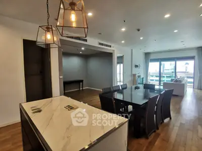 Spacious modern living room with elegant dining area and open layout, featuring stylish lighting and hardwood floors.