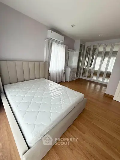 Spacious bedroom with mirrored wardrobe and elegant bed in modern apartment.