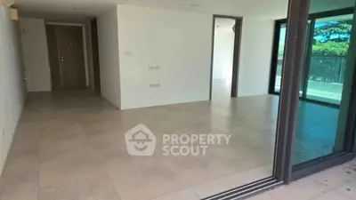 Spacious modern apartment with large windows and balcony access, offering ample natural light and open living space.