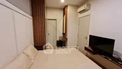 Modern bedroom with minimalist design, featuring a wall-mounted TV and air conditioning unit.