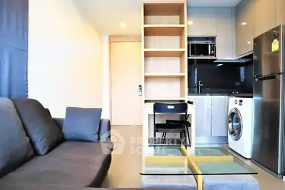 Modern living room with sleek kitchen, featuring washing machine and microwave, ideal for urban living.