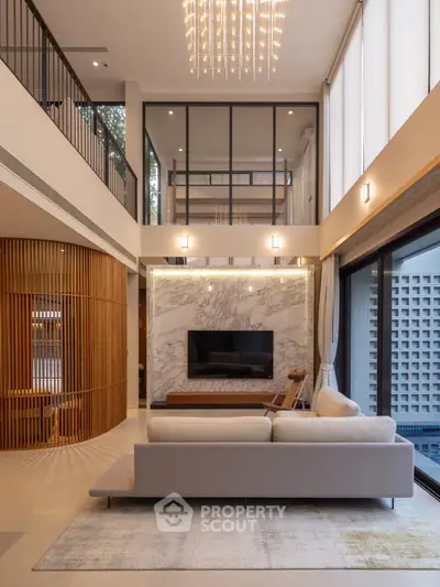 Luxurious modern living room with high ceilings, elegant chandelier, and stylish marble TV wall.