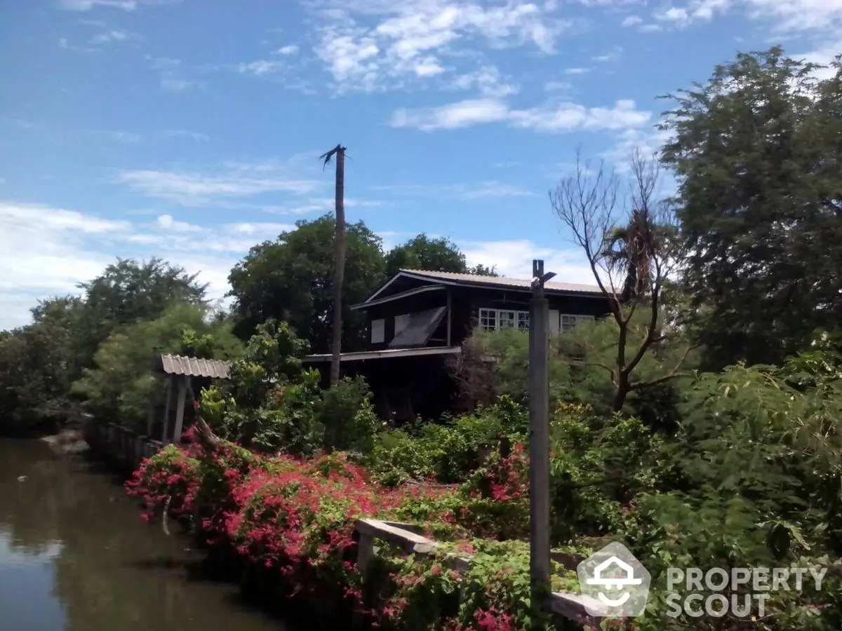 Charming rustic cabin surrounded by lush greenery and vibrant flowers, offering a serene waterfront retreat with a touch of natural beauty.