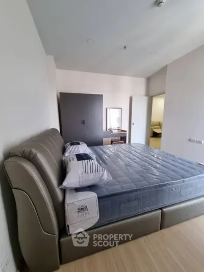 Spacious and well-lit bedroom with a large bed and modern furniture, featuring a sleek design and a comfortable living space.