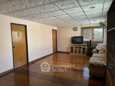 Spacious living room with wooden flooring and decorative ceiling tiles