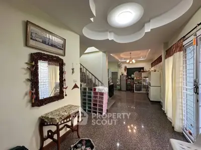 Spacious living room with elegant ceiling design and natural light, featuring a staircase and modern decor.