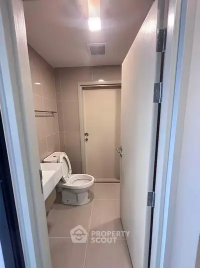 Modern bathroom with sleek design and neutral tiles, featuring a toilet and sink.