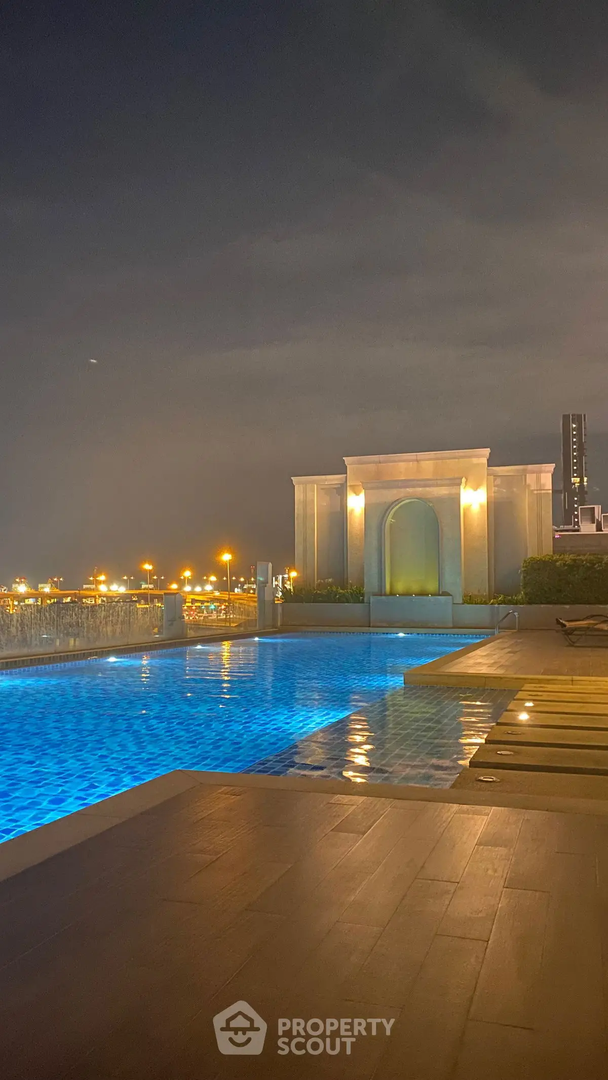 Luxurious rooftop pool with stunning city night view, perfect for relaxation and entertainment.