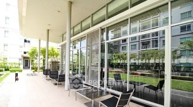 Modern apartment building with spacious outdoor seating area and lush greenery.