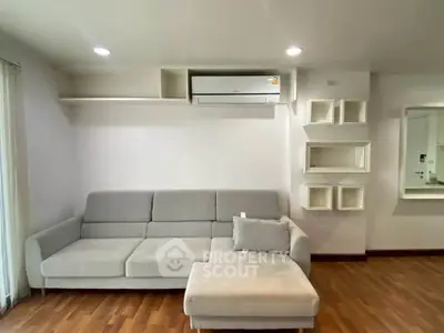 Modern living room with sleek gray sofa and wall-mounted air conditioner, perfect for comfortable living.