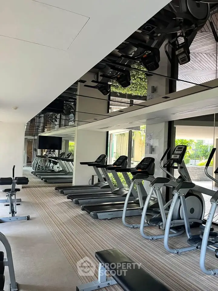 Modern gym with state-of-the-art equipment and mirrored walls in luxury residential building.