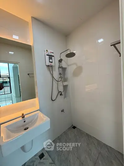 Modern bathroom with sleek shower and illuminated mirror in contemporary apartment.
