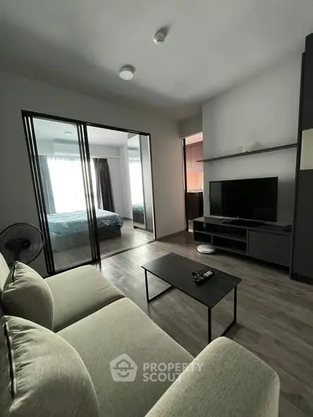 Modern living room with sleek furniture and view into cozy bedroom