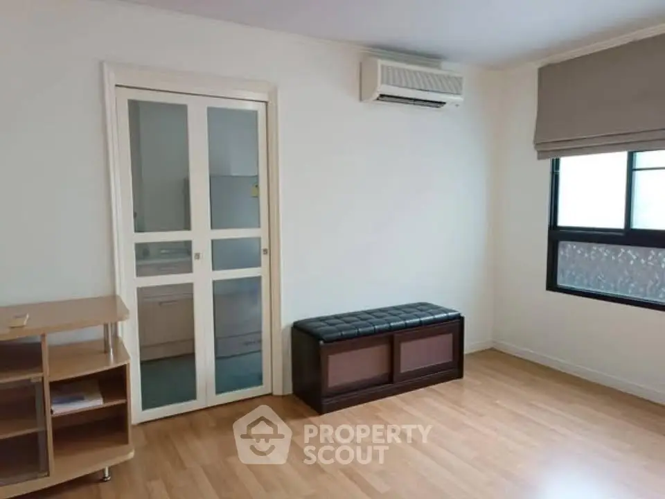 Spacious room with wooden flooring, sliding door, and air conditioning unit.