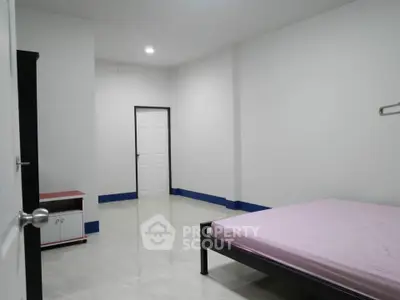 Spacious minimalist bedroom with simple furnishings and white walls