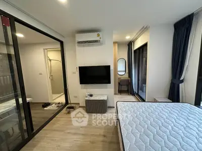 Modern bedroom with glass partition, wall-mounted TV, and stylish decor
