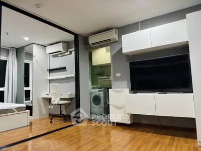 Modern apartment interior with wooden flooring, wall-mounted TV, and in-unit laundry facilities.