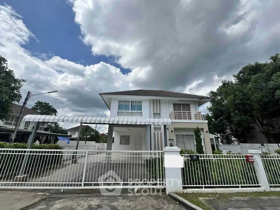 Stunning two-story modern house with gated driveway and lush greenery.