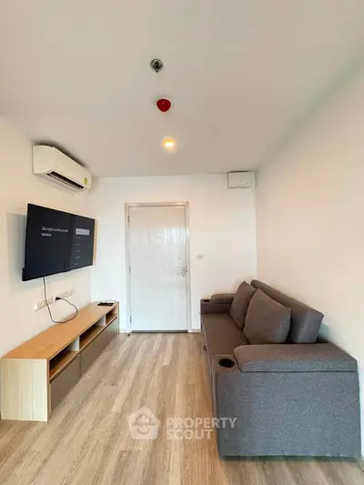 Modern living room with sleek design, featuring a comfortable gray sofa, wall-mounted TV, and stylish wooden flooring.