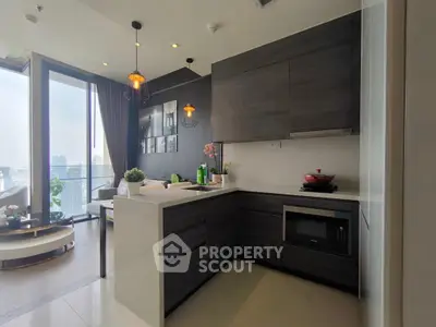 Modern kitchen with sleek cabinetry and open layout in high-rise apartment with city view.