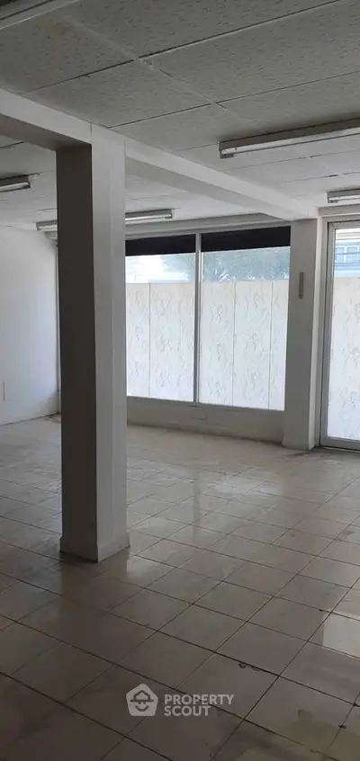 Spacious empty room with large windows and tiled flooring, ideal for customization.
